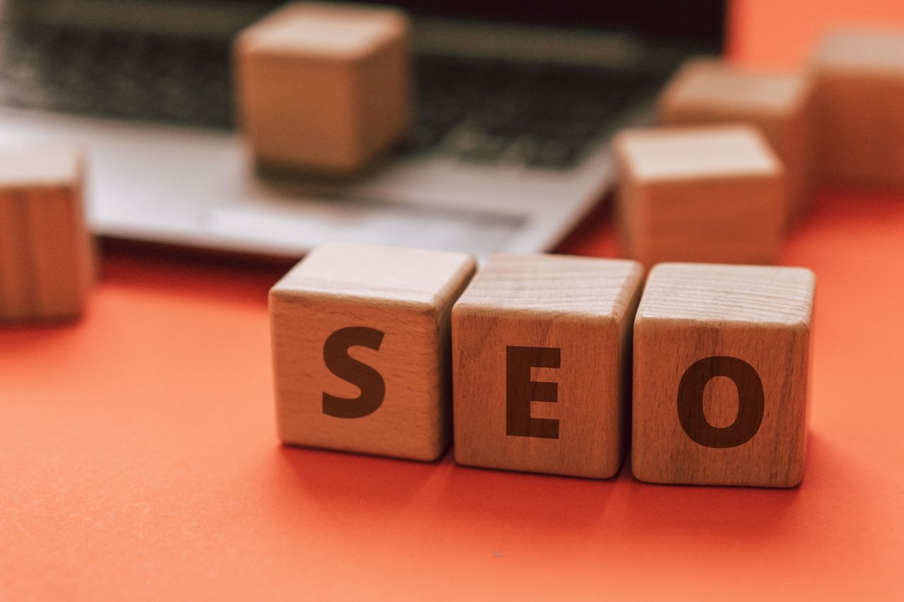 Wooden blocks spelling SEO on a laptop keyboard represent digital marketing concepts.